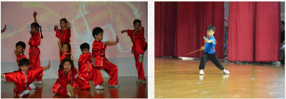 Children in red uniforms perform martial arts on stage; a boy in blue holds a stick in a wide stance.